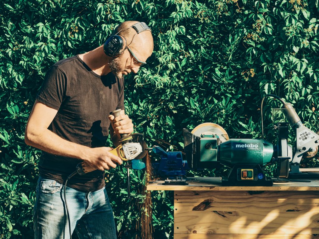 Artisan coutelier découpant de l’acier inoxydable pour la fabrication d’un couteau de cuisine artisanal dans son atelier à Chambéry en Savoie.