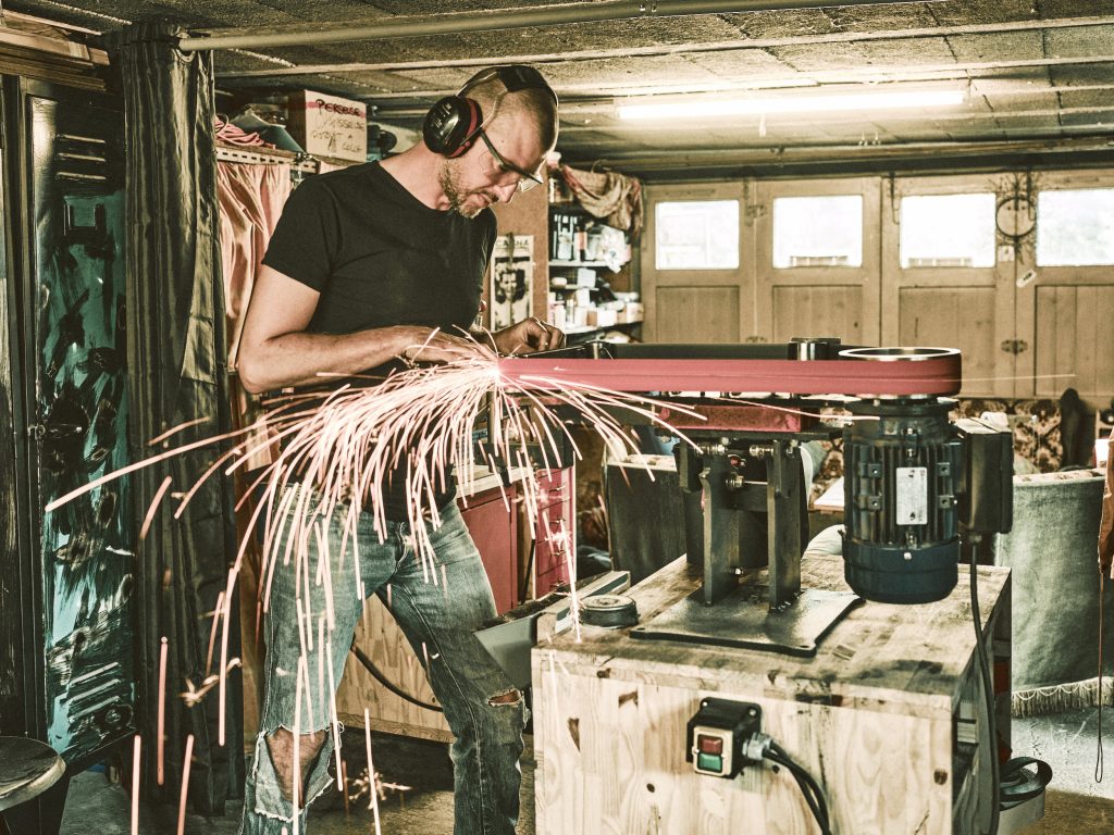 Coutelier artisanal en Savoie en train de poncer et mettre en forme un couteau de cuisine fait main