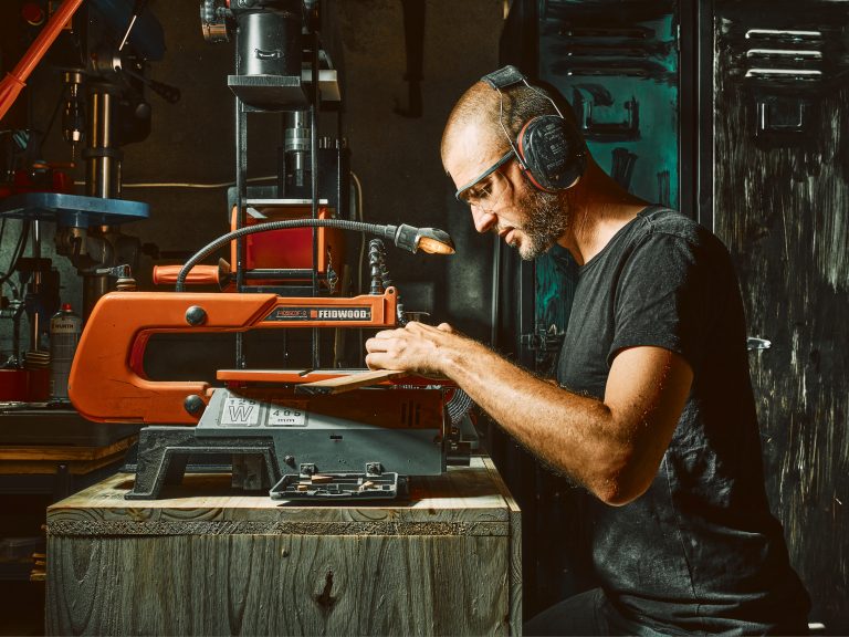 Coutelier artisanal en Savoie découpant des plaquettes de bois pour le manche d’un couteau de cuisine fait main