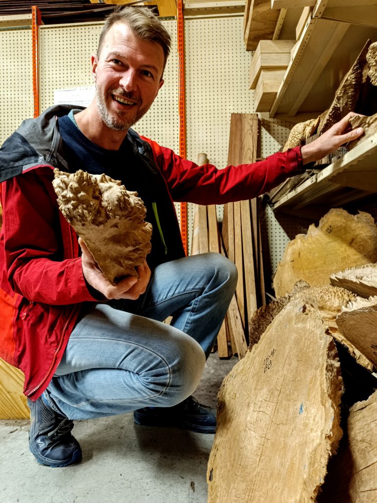 Artisan coutelier choisissant différentes essences de bois pour fabriquer des manches de couteaux artisanaux dans son atelier près de Chambéry en Savoie.