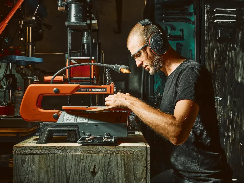 Coutelier artisanal en Savoie découpant des plaquettes de bois pour un manche de couteau