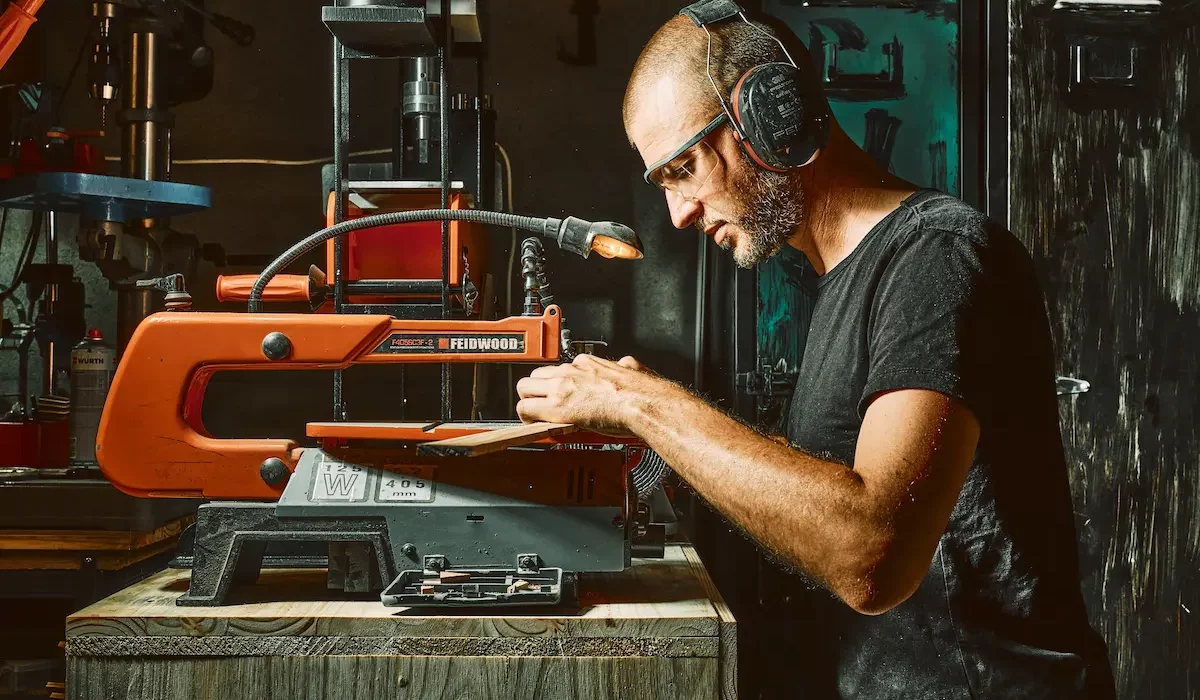 Coutelier artisanal en Savoie découpant des plaquettes de bois pour un manche de couteau