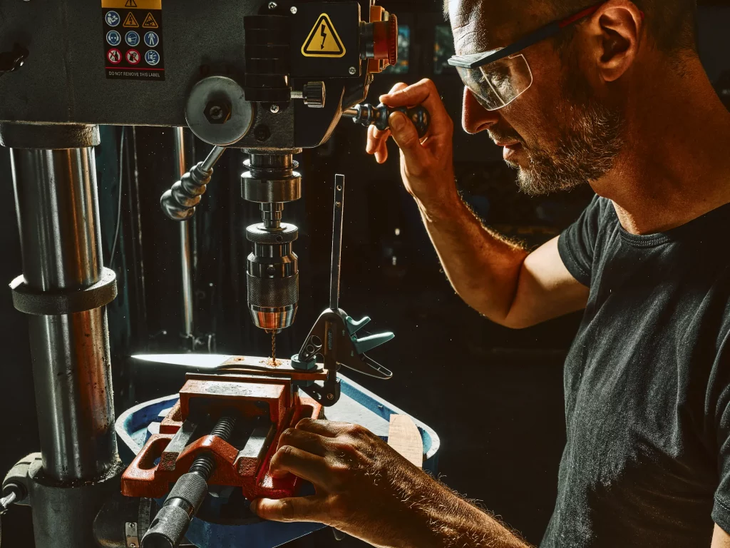 Coutelier artisanal en Savoie perçant des plaquettes de bois pour fabriquer un manche de couteau de cuisine