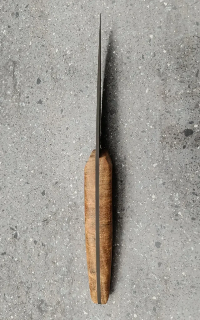 Vue du dos d’un couteau de cuisine artisanal avec lame damas et manche en bois